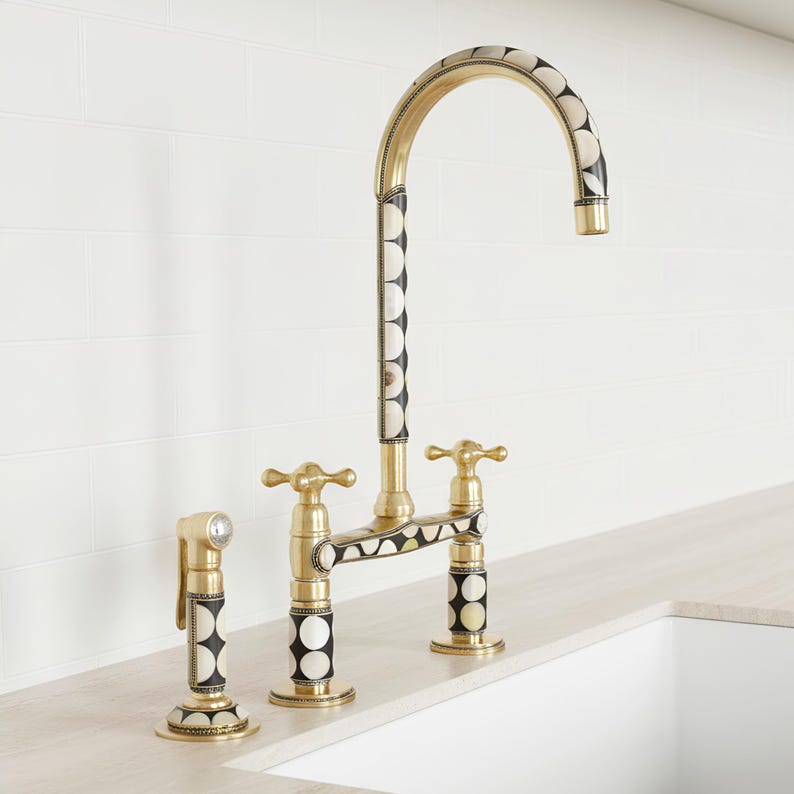 Angled view of handmade brass bridge kitchen faucet with dual handles