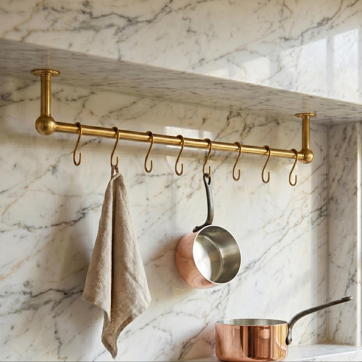 Angled view of handmade brass kitchen rail with hooks