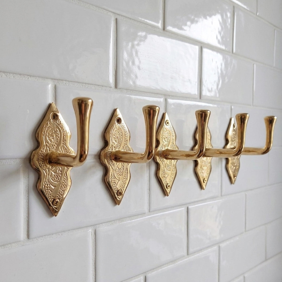 Angled view of solid brass wall hook with engraving