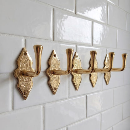 Angled view of solid brass wall hook with engraving