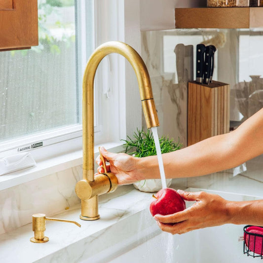 Angled view of unlacquered brass pull-down kitchen faucet