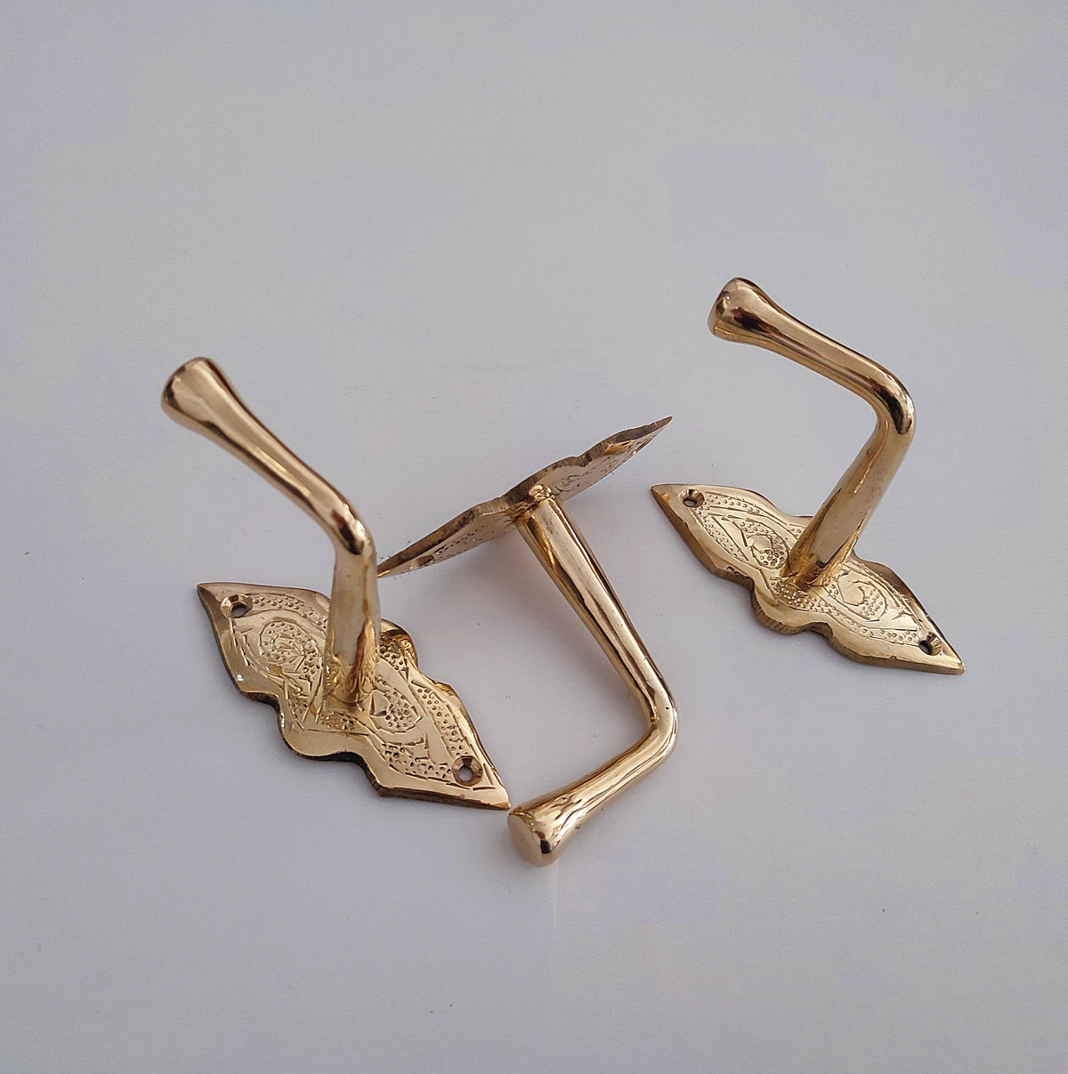 Close-up of hand-engraved detailing on brass wall hook