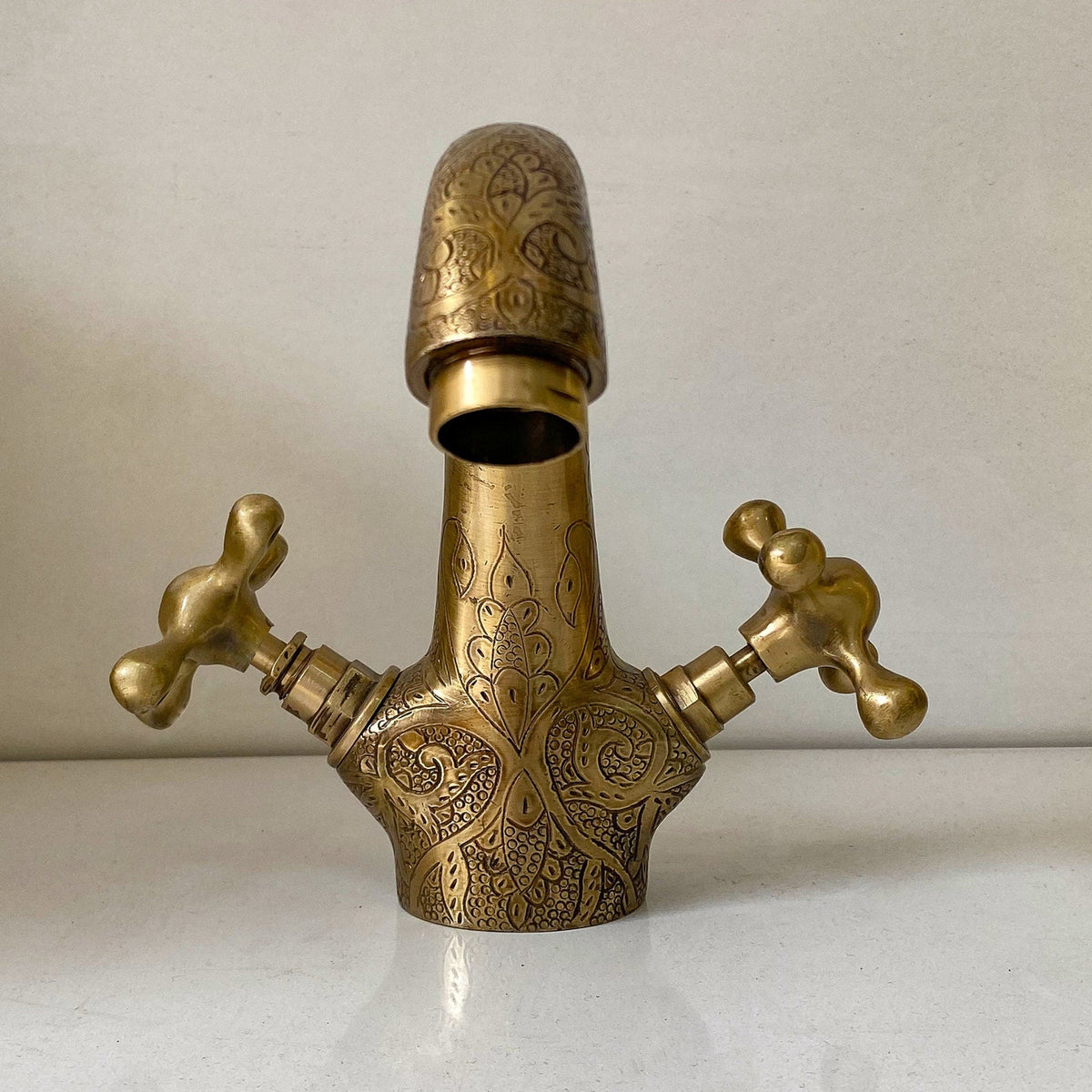 Close-up of the hand-engraved cross handles on the solid brass bathroom faucet