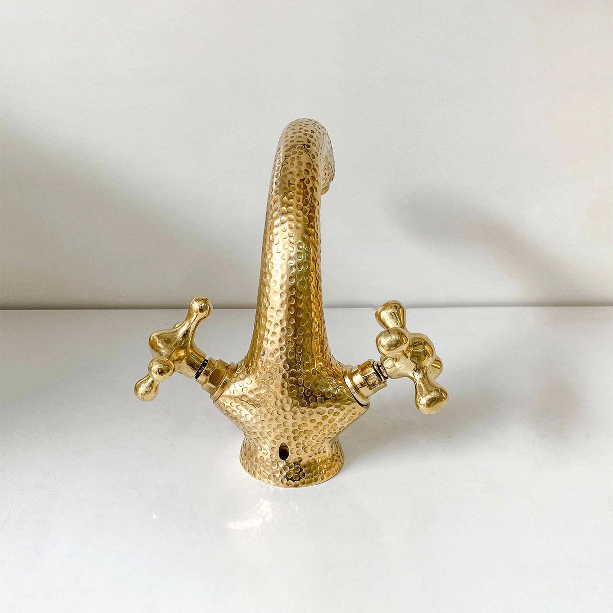 Detailed view of the curved spout on a handcrafted unlacquered brass bathroom faucet