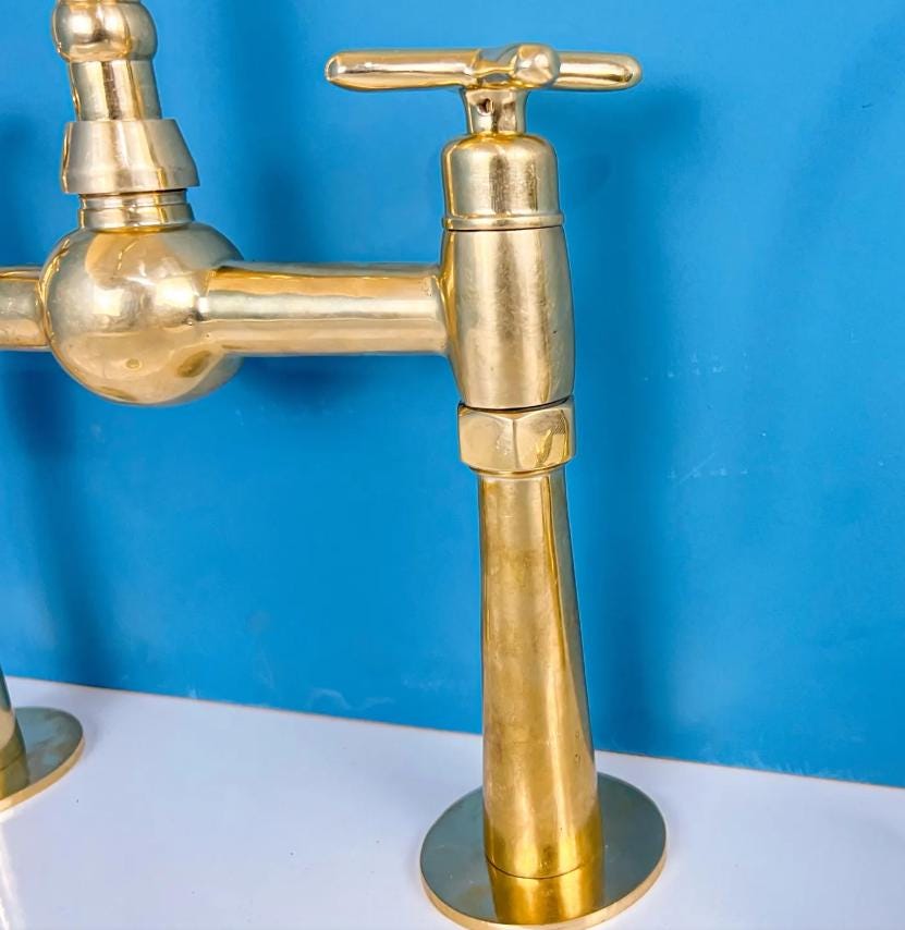 Handles on unlacquered brass wall mount faucet