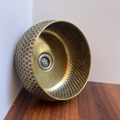 Round unlacquered brass vessel sink on a countertop vanity