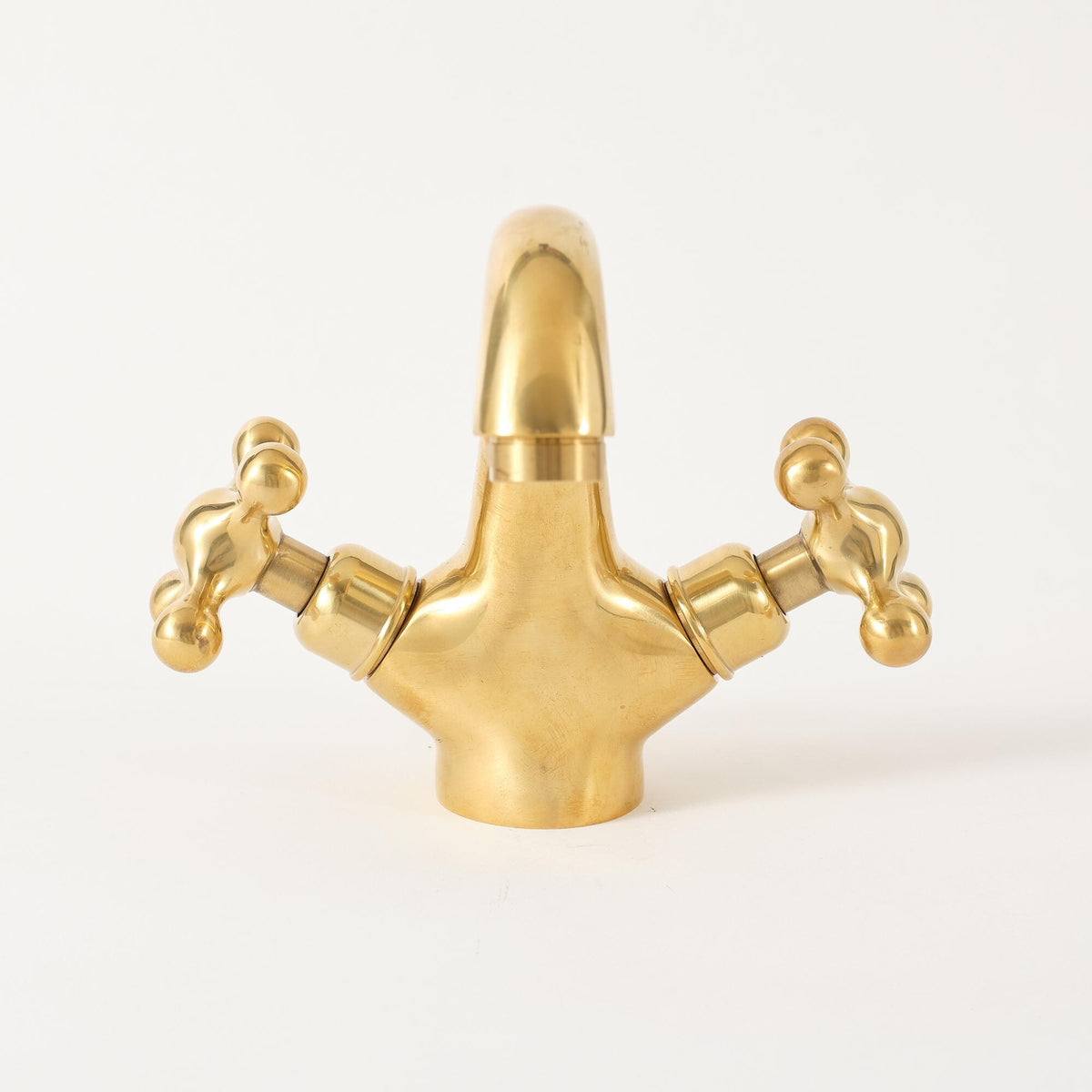 Side angle of solid brass 3-hole bathroom faucet showing curved spout and cross handles