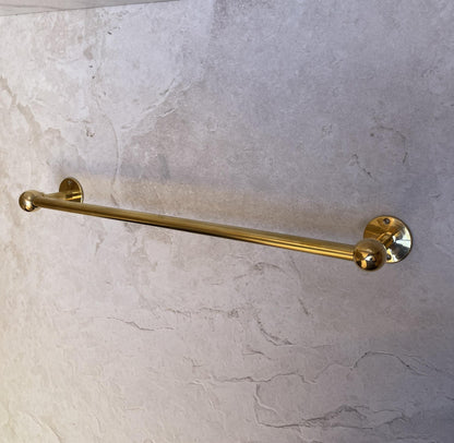 Wall mounted brass towel holder with a living brass finish