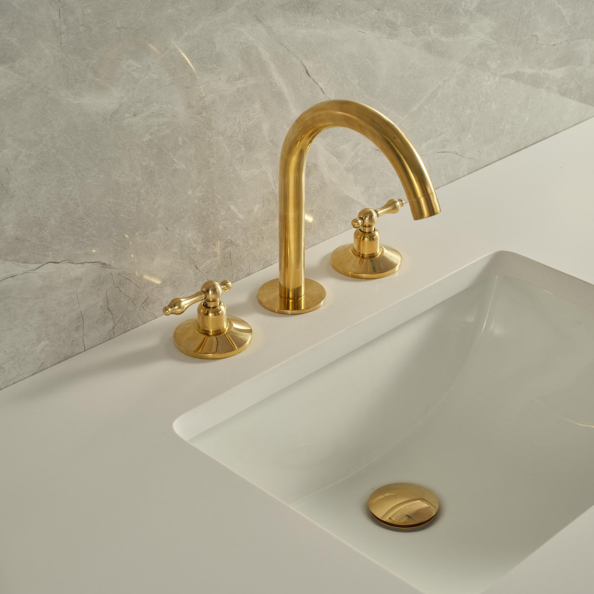 Angled view of unlacquered brass vanity sink faucet with gooseneck spout