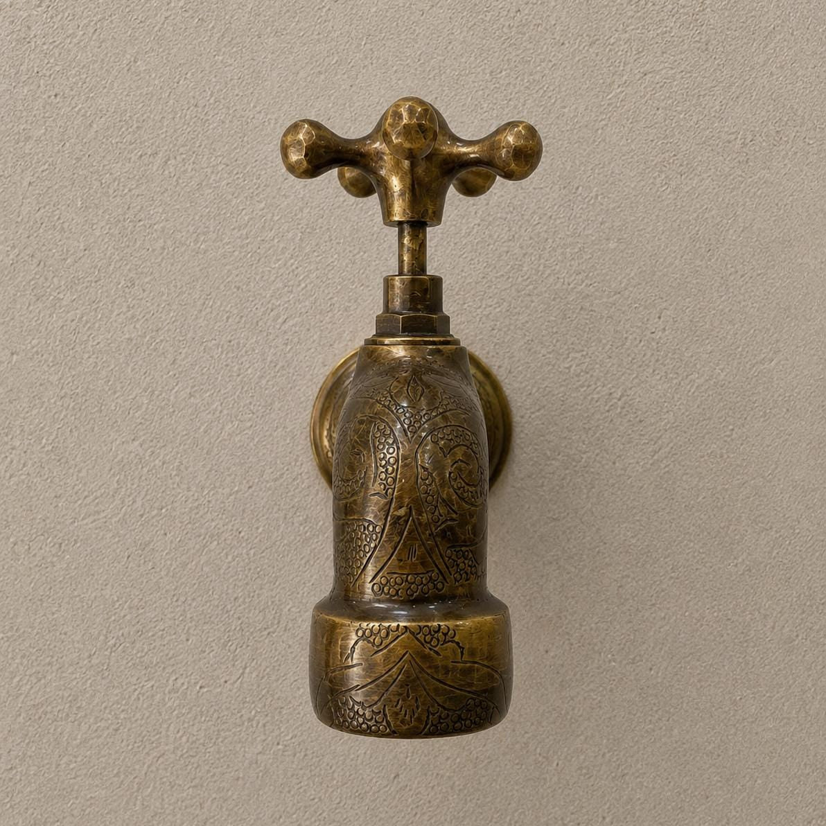 Angled view of handmade engraved brass wall faucet in bronze
