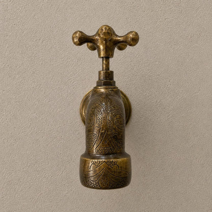 Angled view of handmade engraved brass wall faucet in bronze