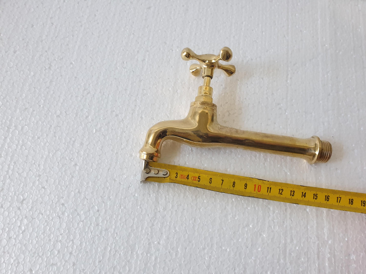 Unlacquered brass wall faucet installed in bathroom sink